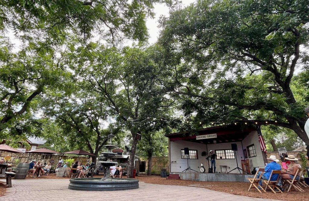 Al fresco dining at the Gruene Grove, where shaded tables under towering trees create a relaxed, park-like atmosphere. Credit: @gruenegrove via Instagram