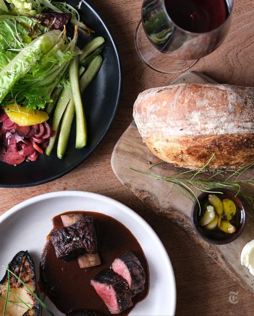 A table full of dishes at Cochineal—fresh salads, artisan bread with garlic confit and sage salt, and a beautifully plated main. Credit: @desertassembly via Instagram