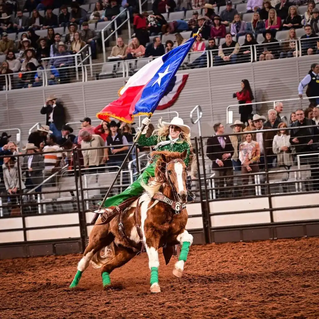 Galloping into tradition — a cowgirl carries the Texas flag at the Fort Worth Stock Show and Rodeo. Credit: u/RodeoBoss66 via r/prorodeo