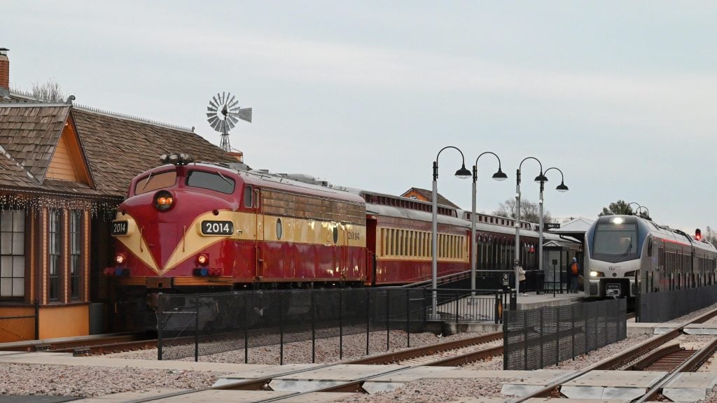 Grapevine Vintage Railroad’s FL9 No. 2014 idles at the historic Cotton Belt/Main Street Station after its 3:30 pm North Pole Express route. , while a sleek TexRail commuter train races past in the background. Credit: Reddit user via r/trains