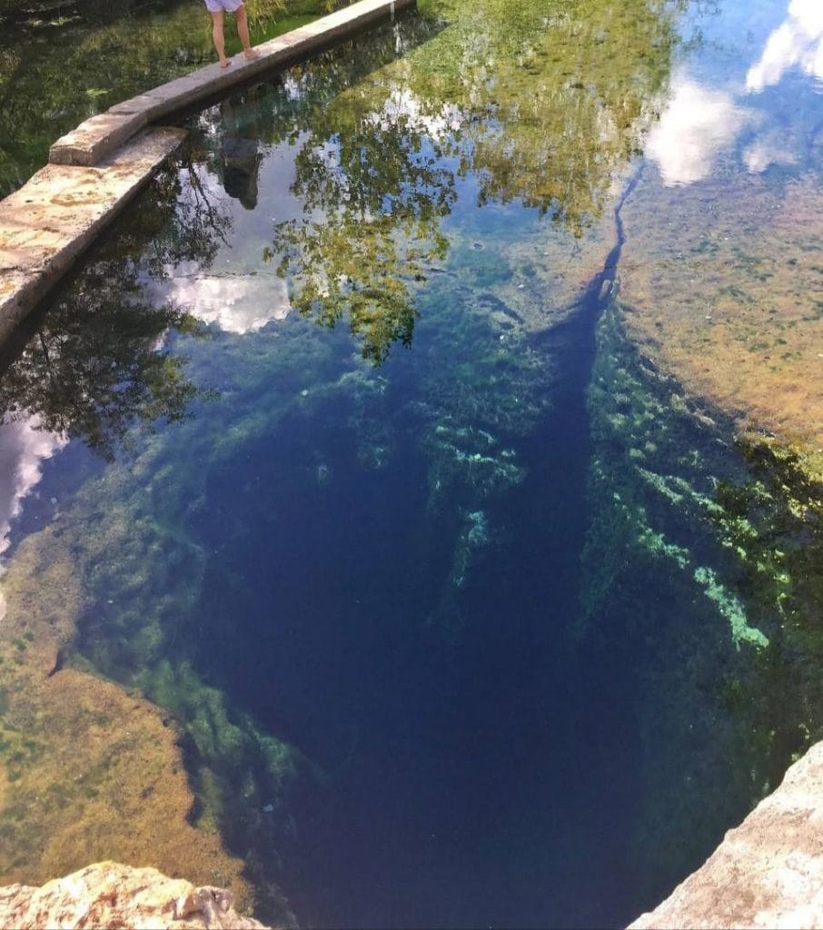 Jacob’s Well drops into darkness, its clear water masking a bottom no one can see. Beneath it lies a maze of ancient caves—deep, cold, and largely unknown. Credit: u/amonaloli12 via r/interestingasfuck