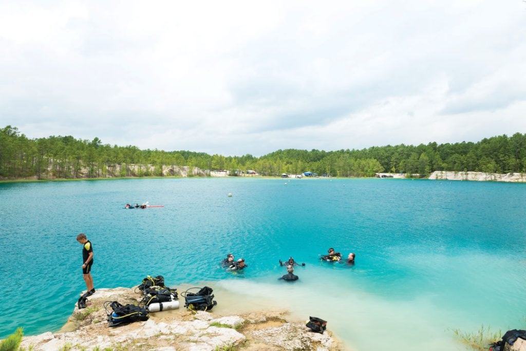 Divers descend into the blue-green waters of Blue Lagoon, uncovering an underwater world beneath the surface. Credit: @houstoniamag via Instagram