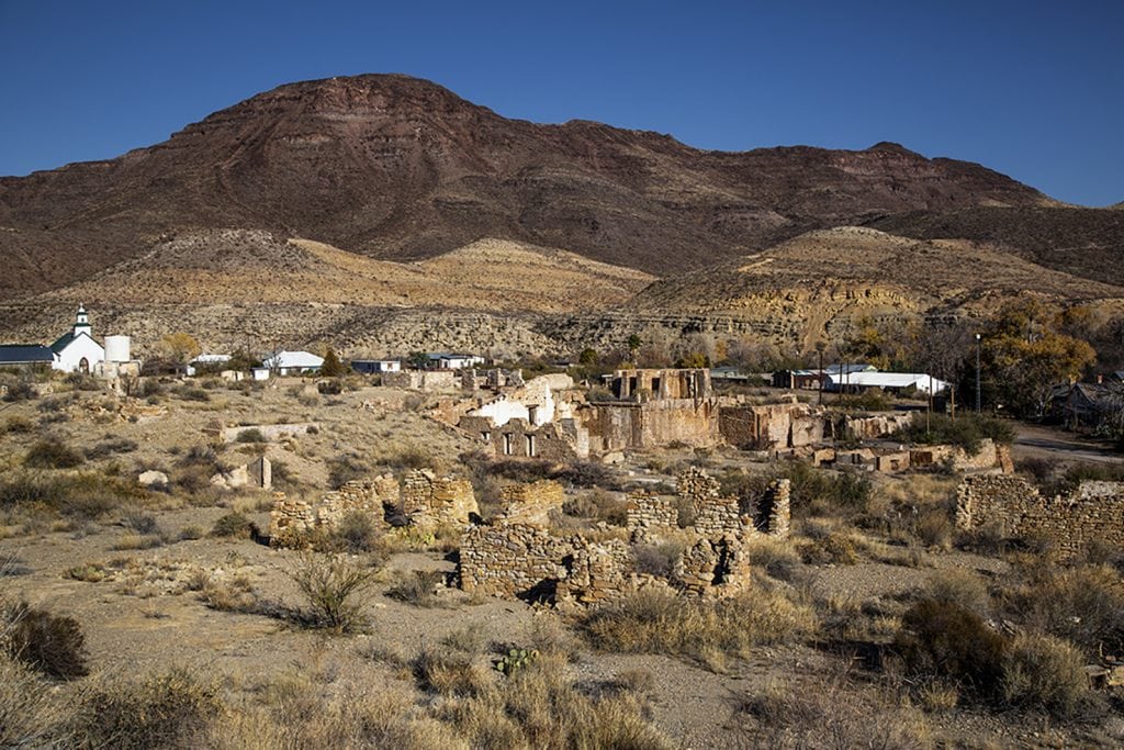 The ghost town of Shafter shows scattered ruins, sparse intact structures, and wide desert land stretching toward distant mountains. Credit: @traces_of_texas via Instagram