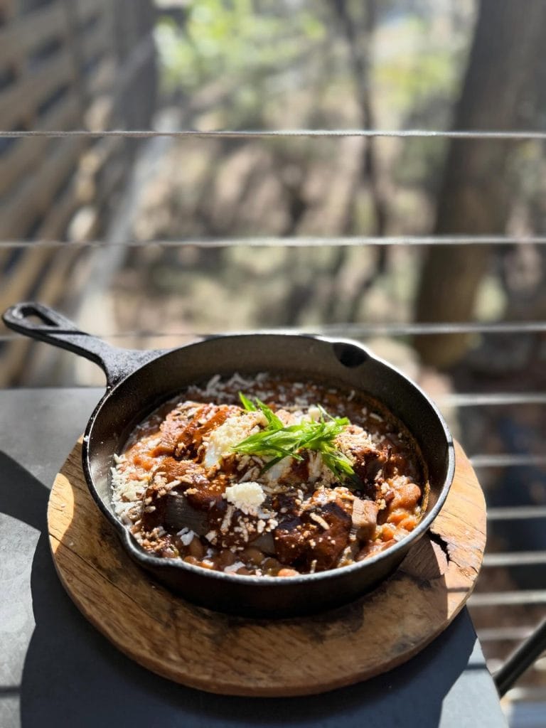 Duck confit tamales topped with mole, paired with charro beans and a slow-cooked egg — a creative take on Texas flavors at The Leaning Pear, a beloved Wimberley dining staple. Credit: @leaningpear via Instagram
