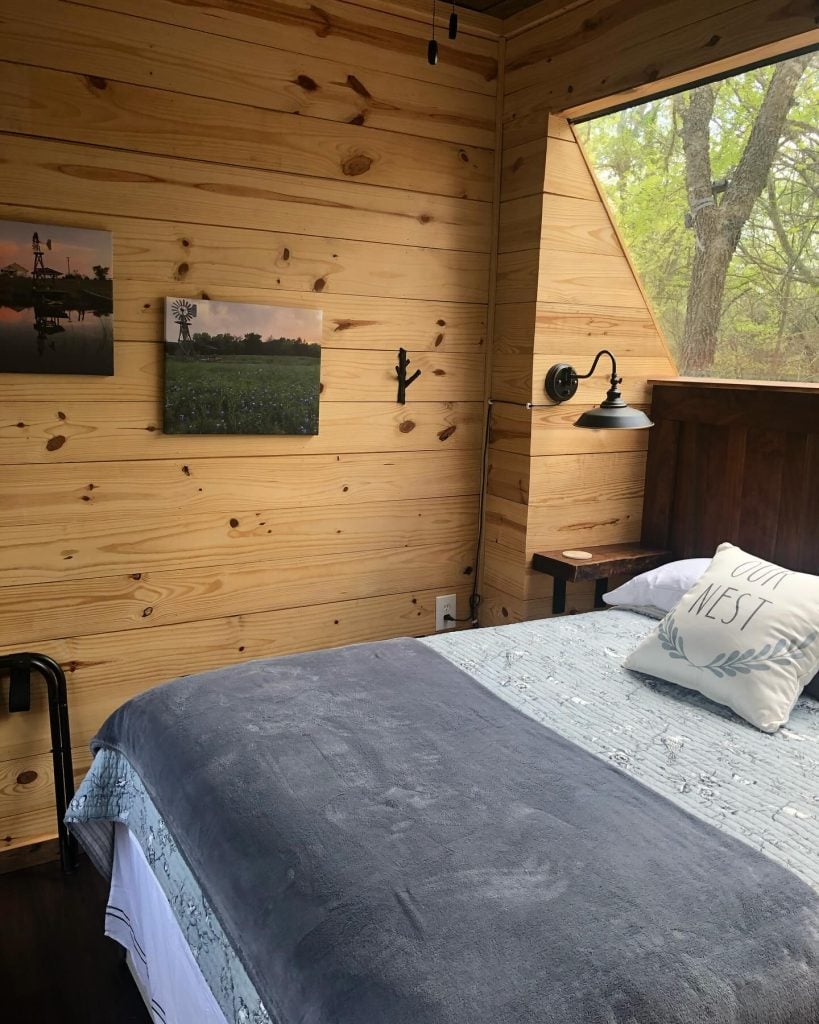 Warm and inviting bedroom at the Air Castle featuring a king-size bed and that signature cozy wooden cabin interior. Credit: @highpointtreehouses via Instagram