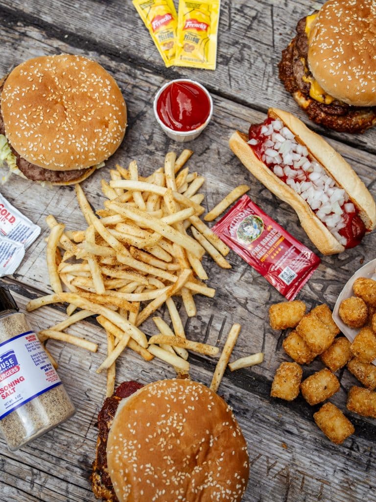 A full spread from Burger House featuring burgers, hot dogs, tater tots, and their famous fries front and center. Credit: @burgerhouseinc via Instagram