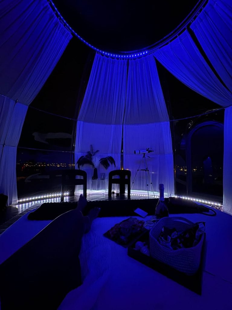 Inside the Star Dome cabin at night, soft blue lighting sets the mood as you stargaze from bed, with a telescope ready for an even closer look at the stars. Credit: @douks_mouna via Instagram