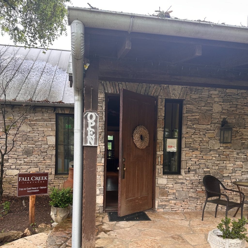 One of the charming guest accommodations at Fall Creek Vineyards features rustic cobblestone walls, a wooden entryway, and a relaxing outdoor patio. Credit: @fallcreekvineyards via Instagram