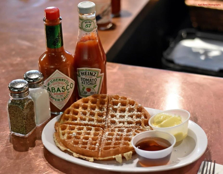 Waffles with syrup, butter, and hot sauce—because how else would a Texan eat breakfast? Absolutely unhinged. Credit: @gritsandgravypdx via Instagram