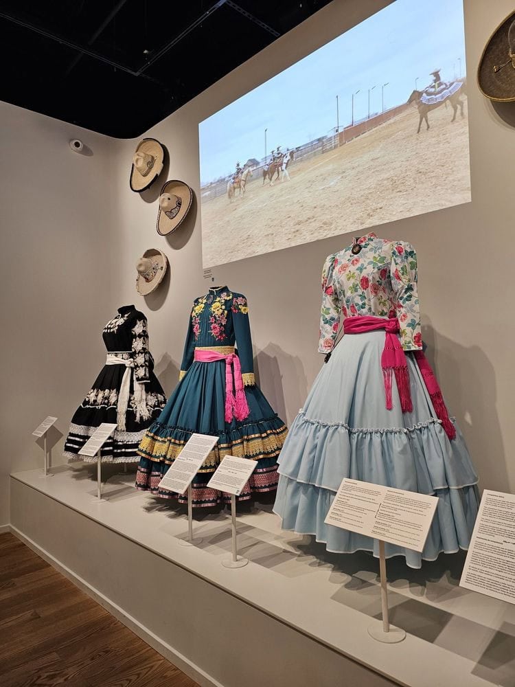 Rodeo dresses worn by cowgirls light up the exhibits with vibrant flower designs, paired with videos showing them in action on horseback. Credit: Delaney S.