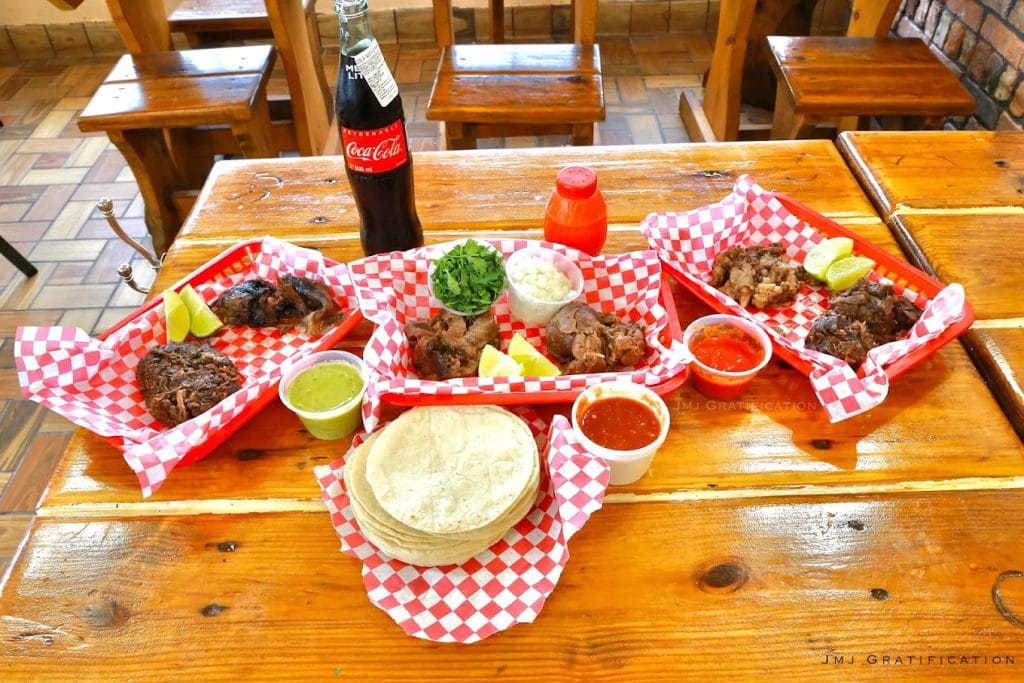A table full of Vera’s barbacoa offerings, served with lime, cilantro, and onions, showcases the flavors of tradition. Credit: JMJ Gratification