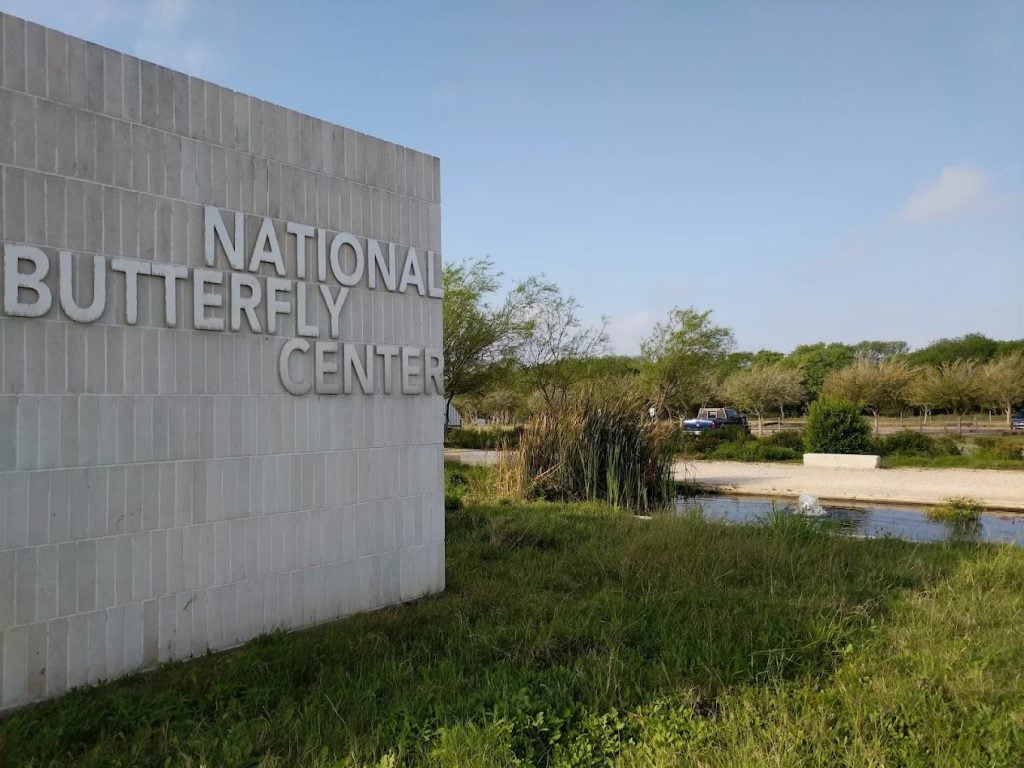 The sign of the National Butterfly Center stands against a backdrop of nature, welcoming visitors to this sanctuary. Credit: Matt Crocker