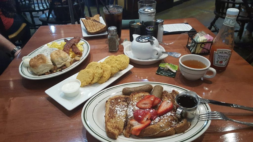 A full spread of breakfast delights—French toast with fruit and sausage, coffee, tea, bacon, eggs, gravy, and biscuits—at Buttermilk Café. Credit: Cathy Ciuba