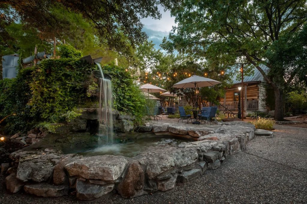 The koi pond and garden provide a relaxing outdoor space with tables, chairs, and umbrellas for unwinding. Credit: Cotton Gin Village