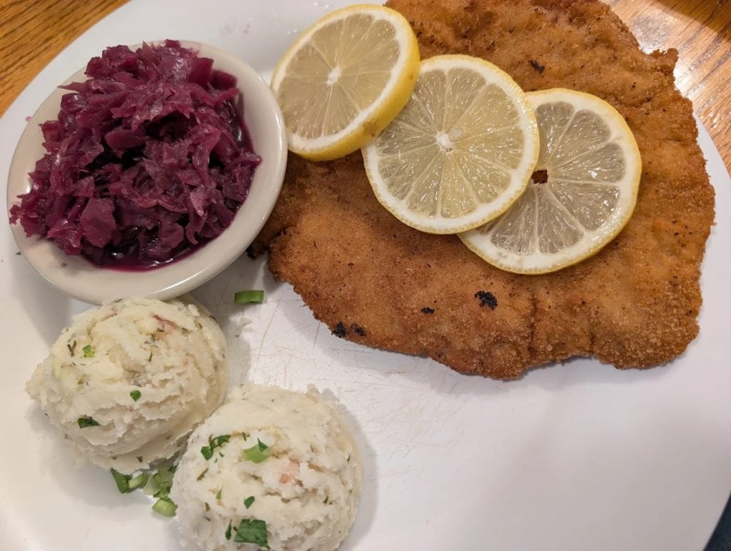 Classic Wienerschnitzel comes with lemon slices, red cabbage, and potato salad for a timeless German favorite. Credit: Gwen Van der Zyppe