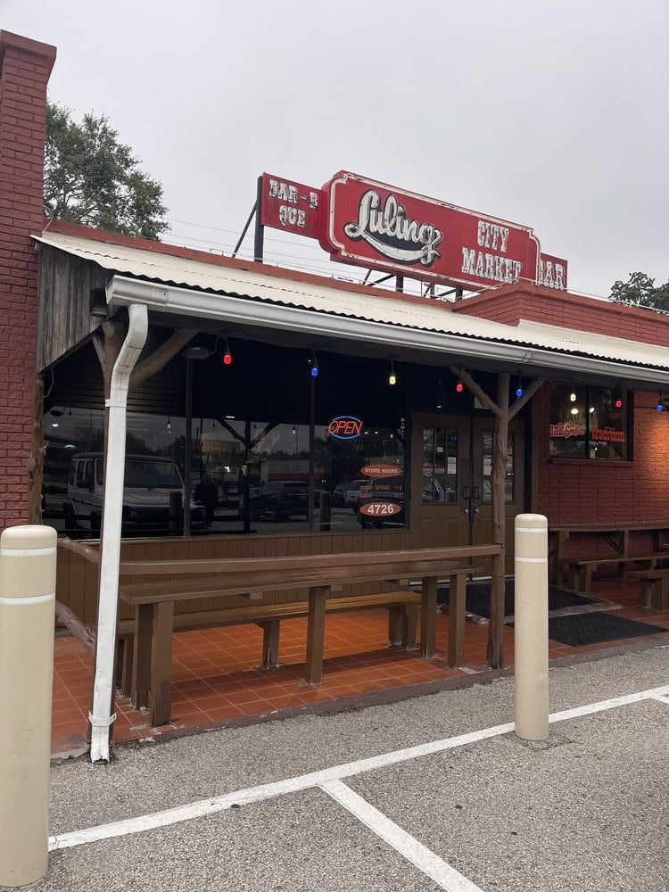The façade of City Market is simple, with a red sign, wooden exterior, and benches for outdoor seating. Credit: Megan V.