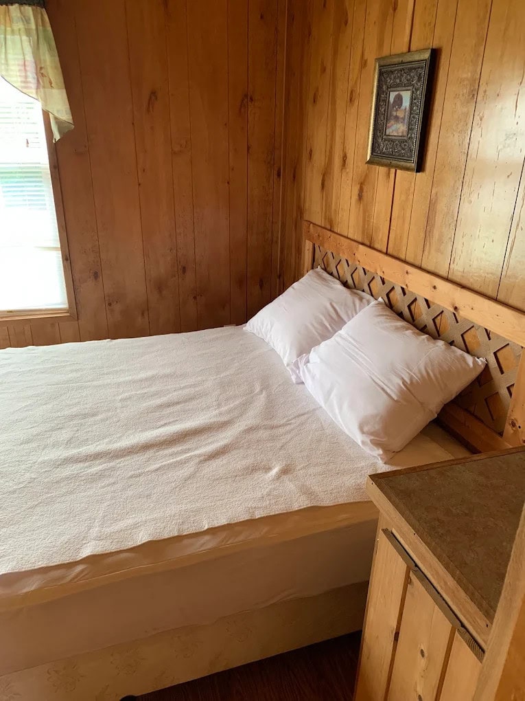A simple, clean bedroom setup with fresh linens, bedside table, and windows ensures restful nights at Jellystone. Credit: Arlettys Carrodeguas