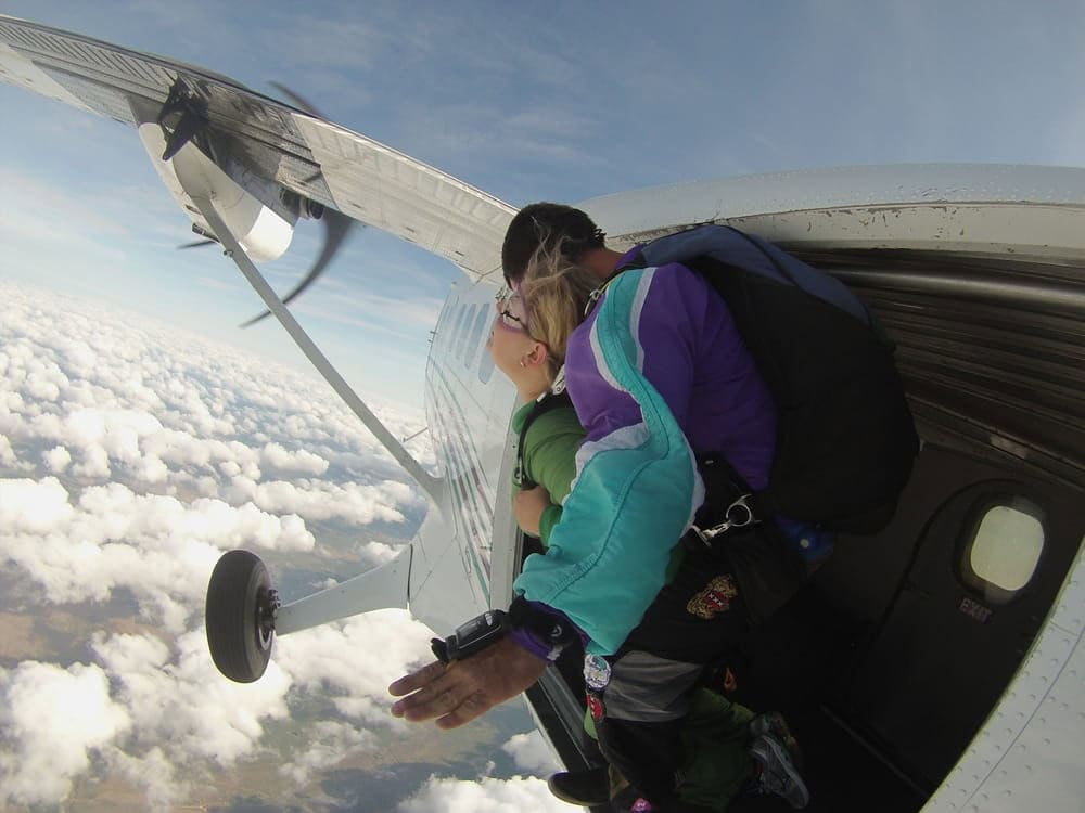 A tandem diver prepares to leap from the plane, capturing the rush of the moment. Credit: Erin H.