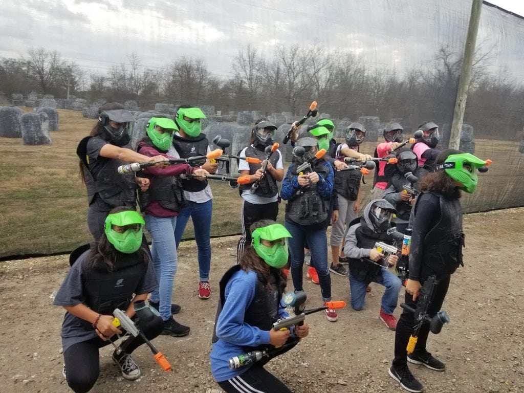 A group of teenagers gear up in full safety equipment, with helmet colors marking their teams. Credit: C. 1.