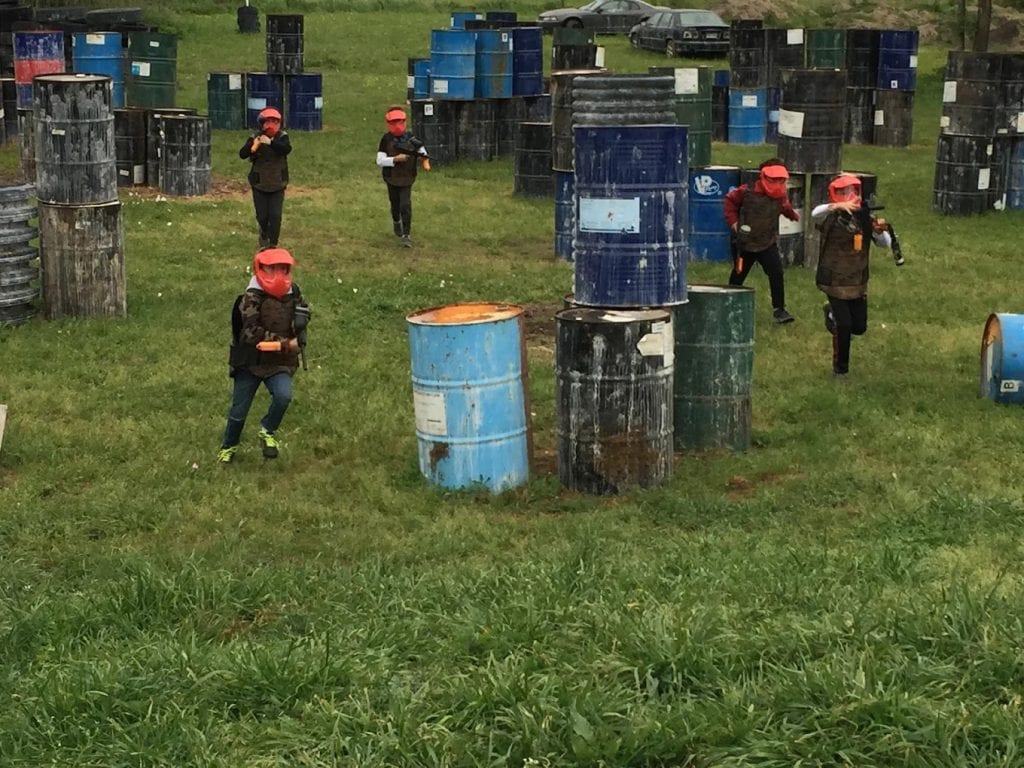 A group of kids play on a field filled with drums, using them as obstacles in their game. Credit: Riki Graves