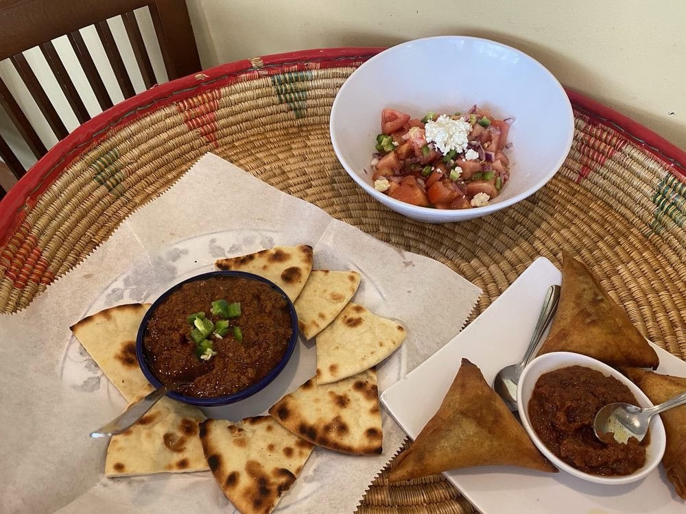 Minchet Abish, beef sambusa, and tomato salad form a delicious appetizer combination. Credit: Helena D.