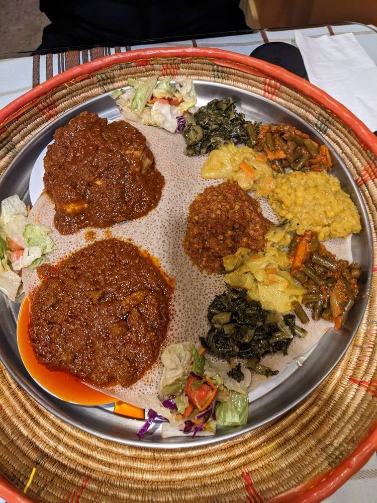 A veggie sampler and two meat entrées are served atop injera, true to Ethiopian tradition.