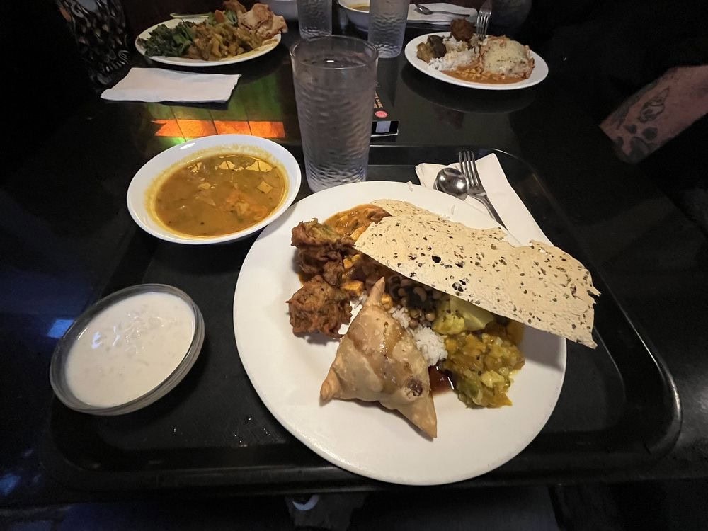 Another plate highlights roti and samosa alongside buffet favorites. Credit: Roshi M.