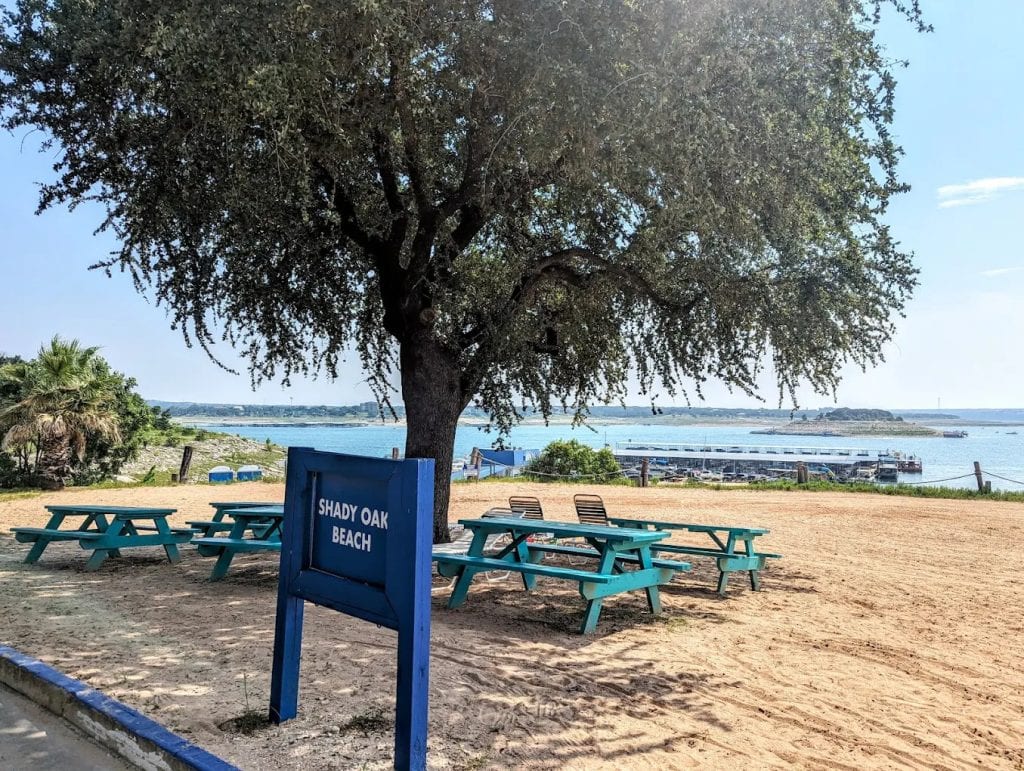 Picnic tables shaded by oak trees overlook Lake Travis, offering a relaxing spot to dine and take in the view. Credit: Ciara Lindley