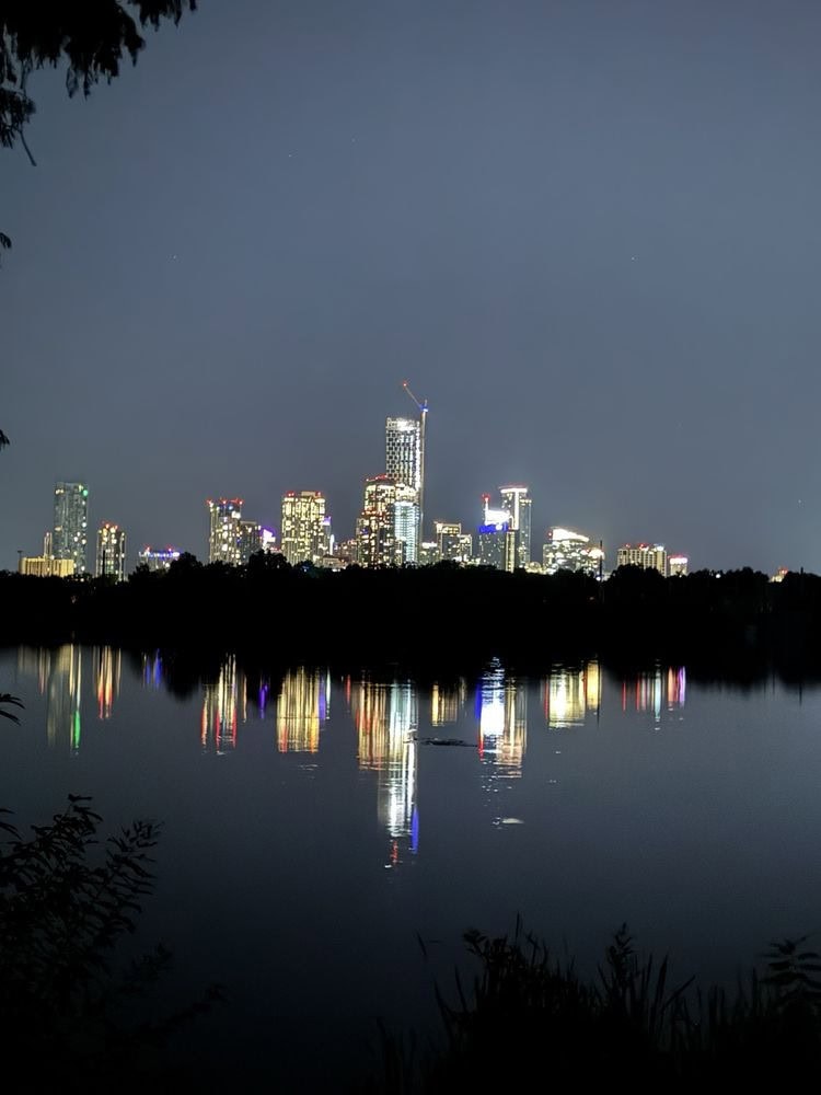 Lady Bird Lake glows at night, reflecting the dazzling Austin skyline in a breathtaking view. Credit: Franklin C.