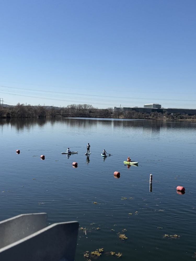 Paddle boarders and kayakers share the water, creating a lively scene of outdoor recreation. Credit: Tracey L.
