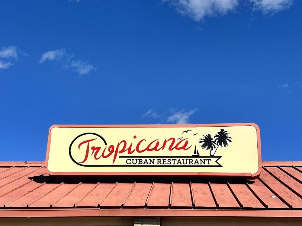 The Tropicana Cuban Restaurant sign is simple yet tropical, featuring boats, birds, and palm trees. Credit: Natalie K.