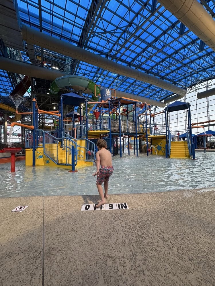A child enjoys Rascal’s Round‑Up, a huge playground set in a shallow pool—kids’ heaven. Credit: S B.