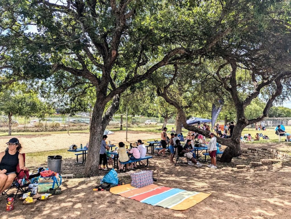 Picnic tables under shady trees and grassy areas invite families to gather for meals and relaxation. Credit: Ciara Lindley