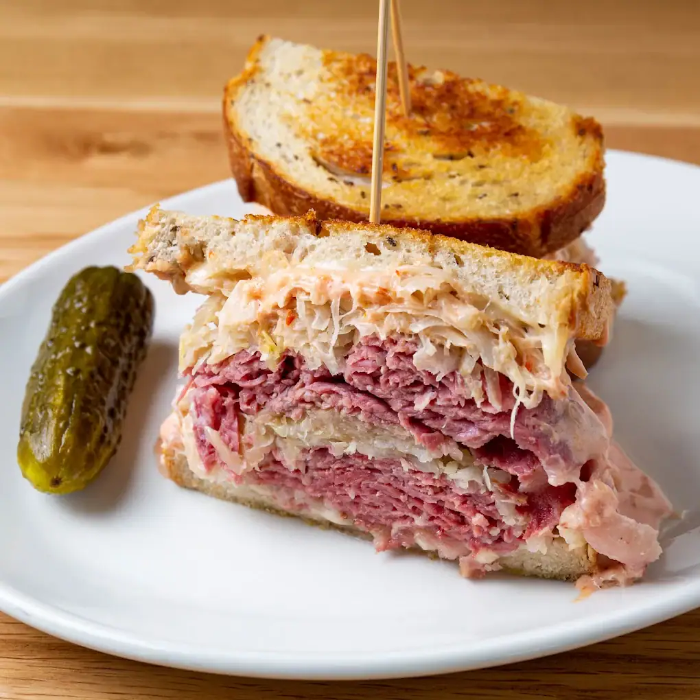 Katz’s pastrami sandwich stacks layer upon layer of juicy meat, never stingy, with a crisp pickle on the side. Credit: Katzs Never Kloses