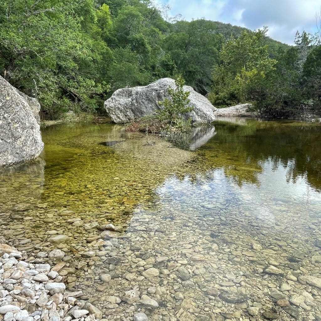 Crystal-clear waters flow through Lost Maples, surrounded by rocky terrain and colorful seasonal foliage. Credit: @lostmaples via Instagram