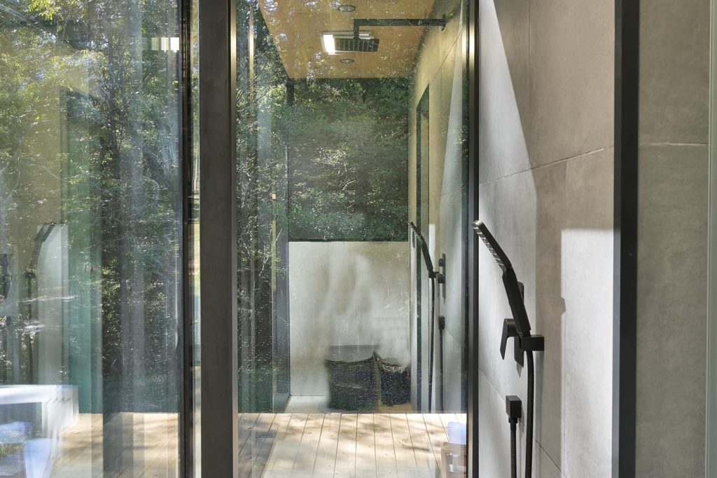 Private bathroom inside the Mirror House with a shower and toilet. Modern, all-black design that feels very spa-like. Credit: @trakksounds via Instagram
