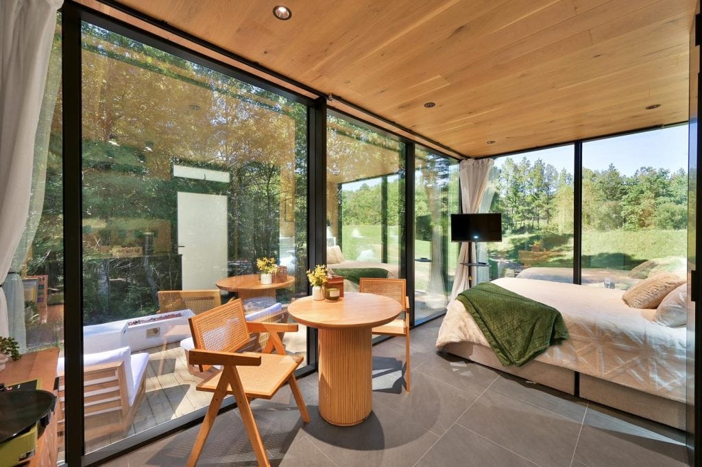 Inside the Mirror House. Cozy modern bedroom with a large bed, dining nook for two, and TV—minimalist but super comfortable. Credit: @trakksounds via Instagram