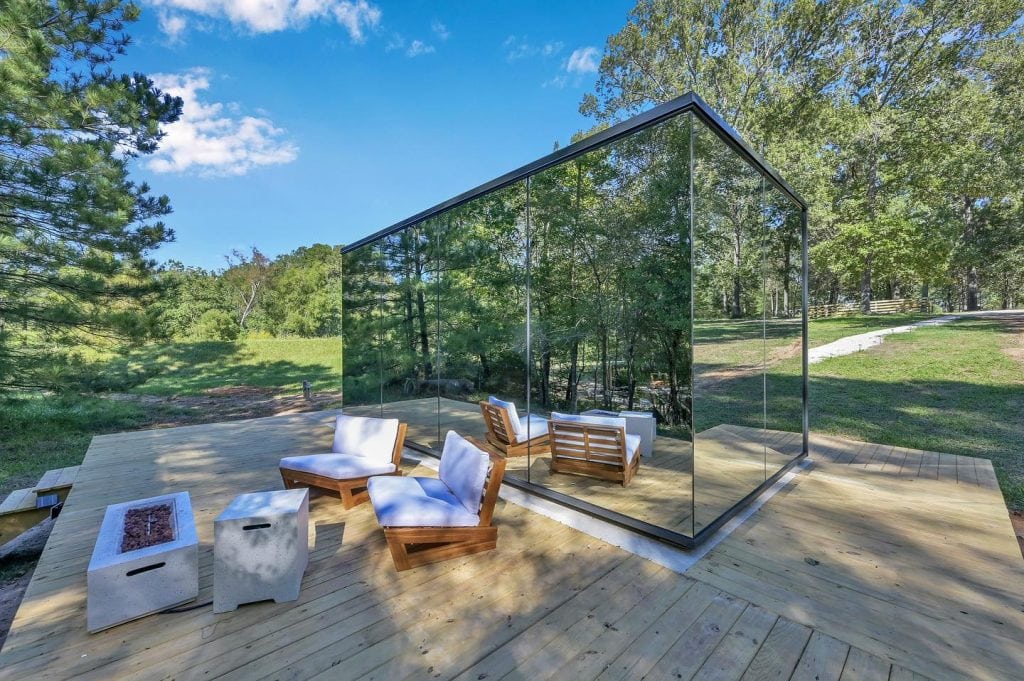 Exterior of the Mirror House at Cameron Ranch, Lake Livingston. Mirrored design with a private patio featuring seating, a fire pit, pizza oven, and grill. Credit: @trakksounds via Instagram