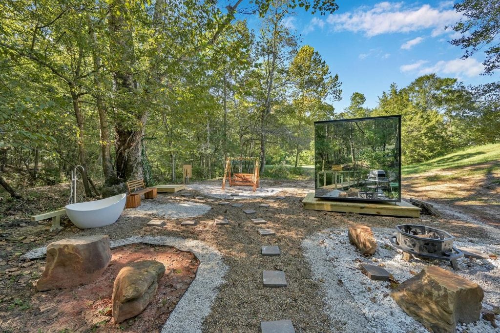 Outdoor space of the Mirror House—complete with a soaking tub, bonfire area, swing, and total immersion in nature. Credit: @trakksounds via Instagram
