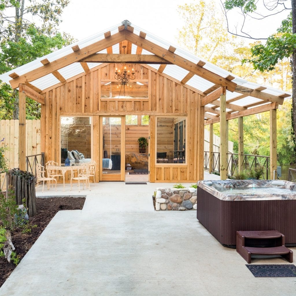 The private exterior of a Naturalist Boudoir cabin features a spacious patio, outdoor dining area, and a secluded jacuzzi surrounded by nature. Credit: @naturalistboudoir via Instagram