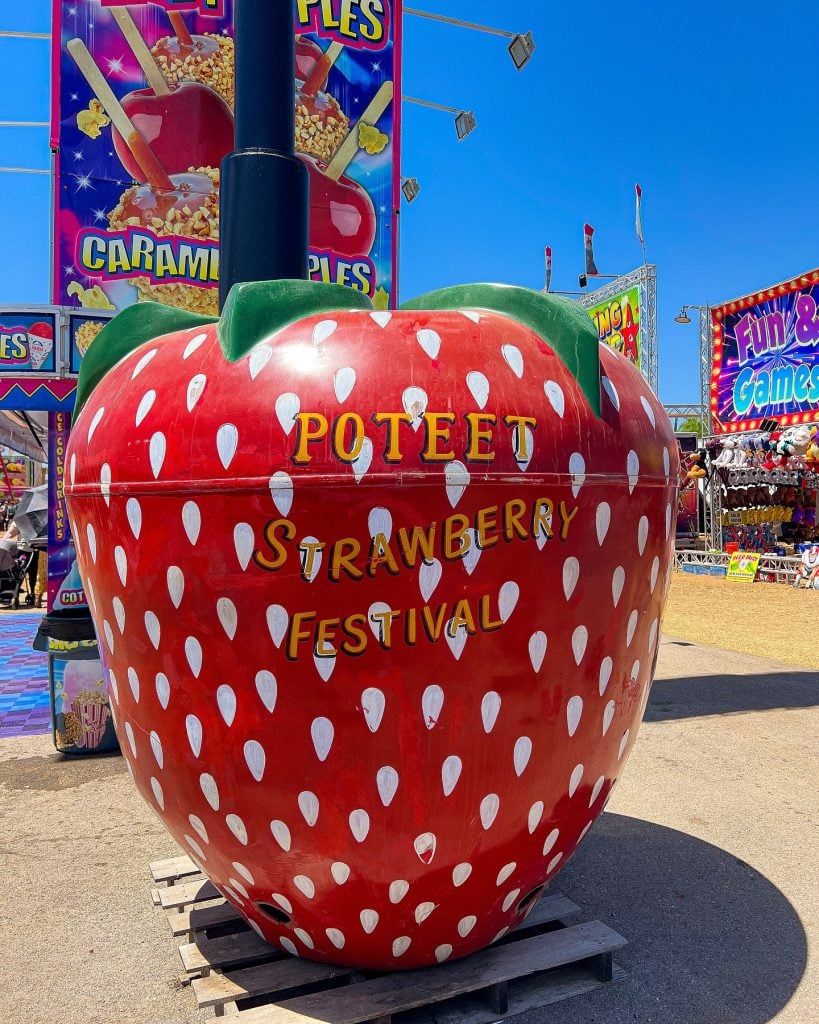 A giant strawberry statue welcomes visitors to the Poteet Strawberry Festival, where everything revolves around strawberries—even strawberry nachos. Credit: @_thepinkplate_ via Instagram