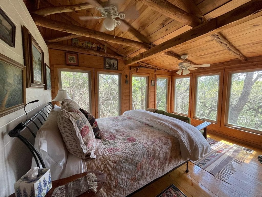 The bedroom inside Salvation Cabin. A cozy wooden retreat with a comfortable bed, antique furniture, and large windows that let you wake up to peaceful nature views. Credit: @lake1290 via Instagram
