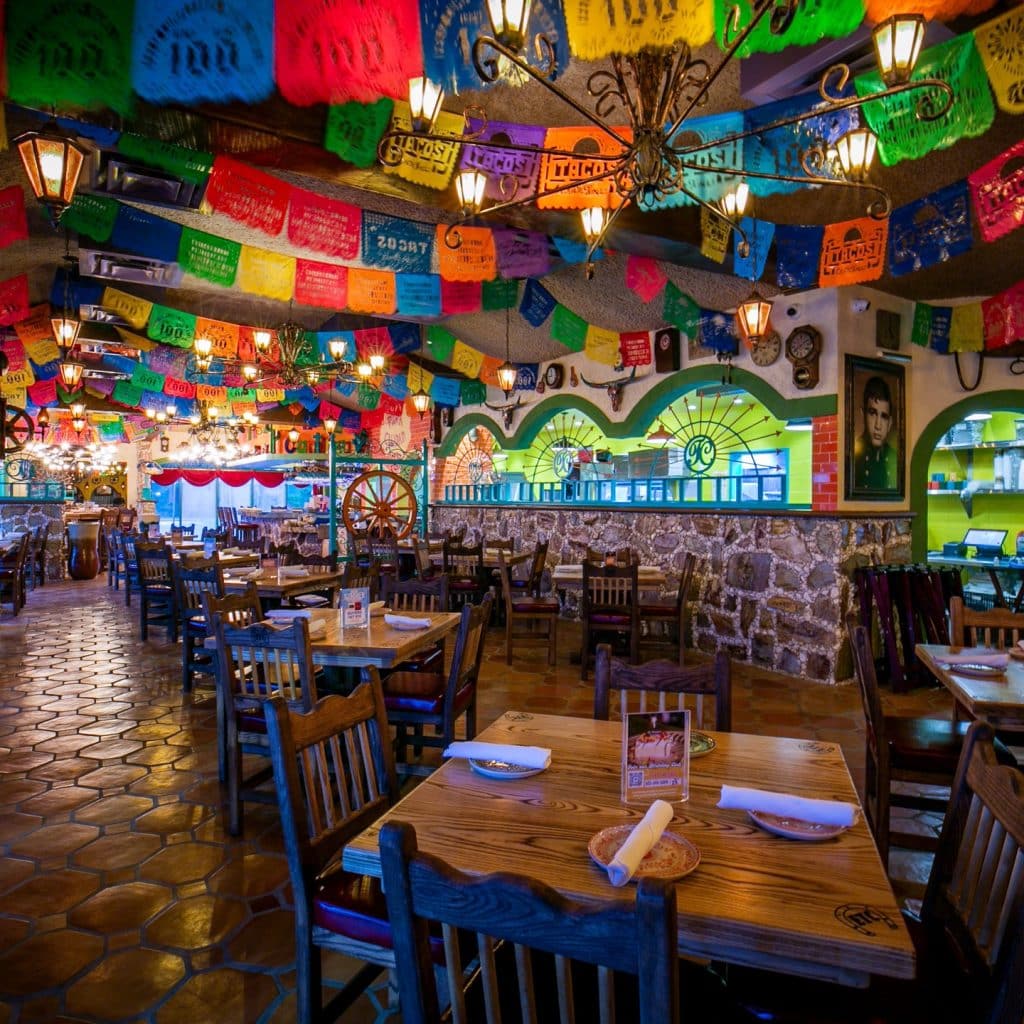 The vibrant interior of El Tiempo Cantina, filled with colorful ceiling banners, cozy seating, and classic Tex-Mex comfort. Credit: @eltiempocantina via Instagram