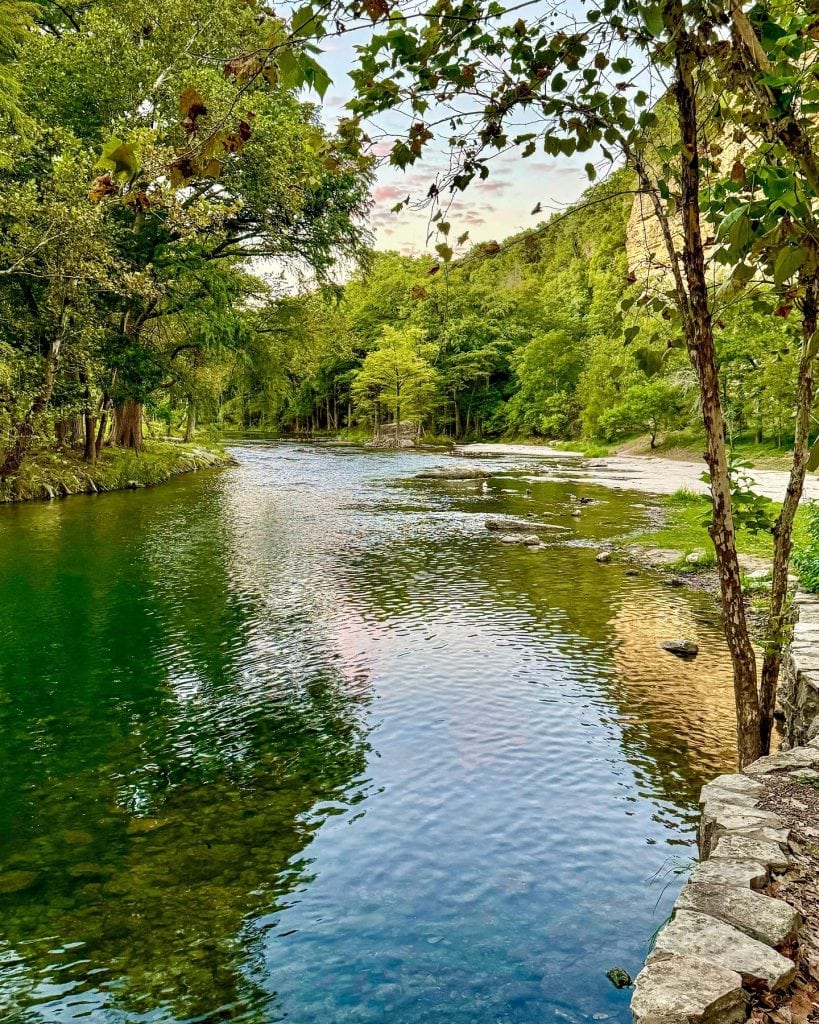 Clear waters and lush surroundings along the Guadalupe River—one of the best places Texans should try tubing. Credit: @inandaroundnbtx via Instagram