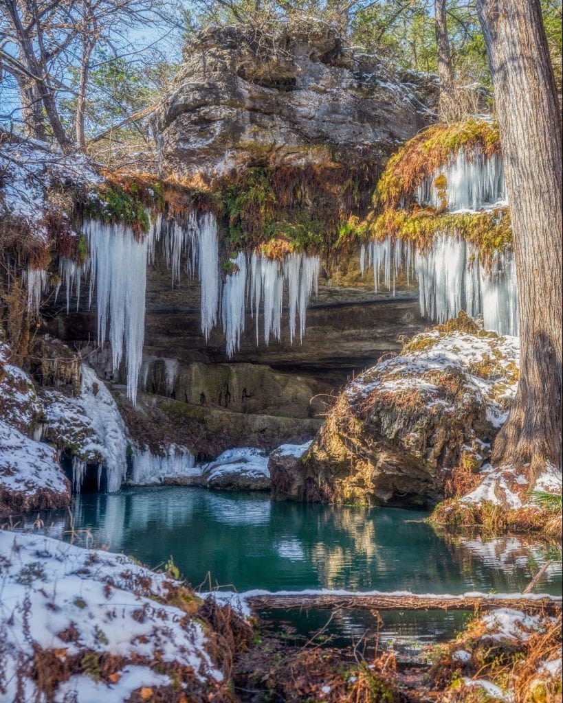 Westcave Preserve after a snowstorm feels unreal—frozen waterfalls forming icicle-like shapes around the grotto, turning the landscape into a rare Texas winter wonderland.