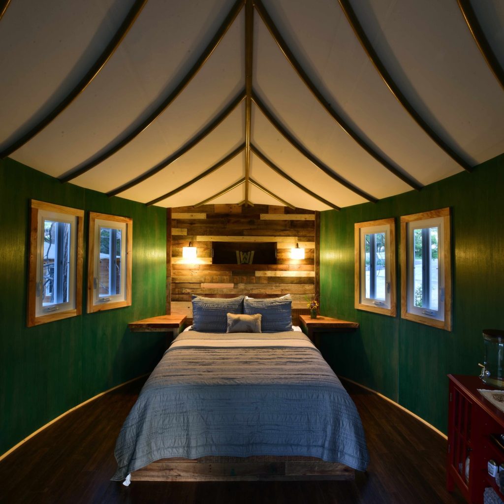 Inside the Willow Treehouse, a cozy queen bed sits beneath a leaf-inspired ceiling, with windows that bring the surrounding nature right in. Credit: @cypressvalleytreehouses via Instagram