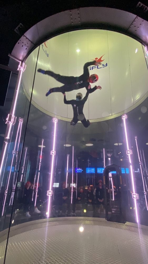 Two people float mid‑air with limbs spread wide, recreating the outdoor skydiving experience in a safer way. Credit: Joyce H.