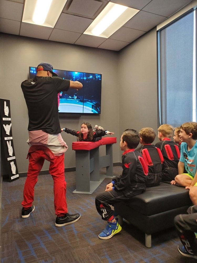 A group of kids listens attentively to an iFLY instructor explaining what to do before flying. Credit: Mary Anna N.