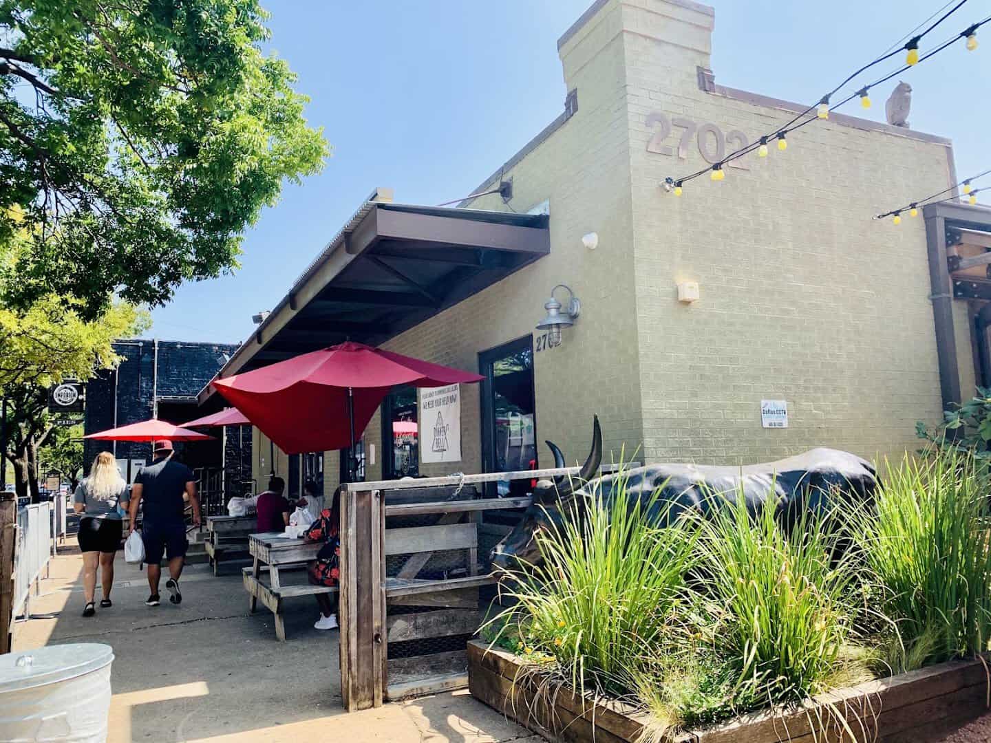 The 2702 Main Street building and red patio umbrellas at Pecan Lodge in Deep Ellum, Dallas