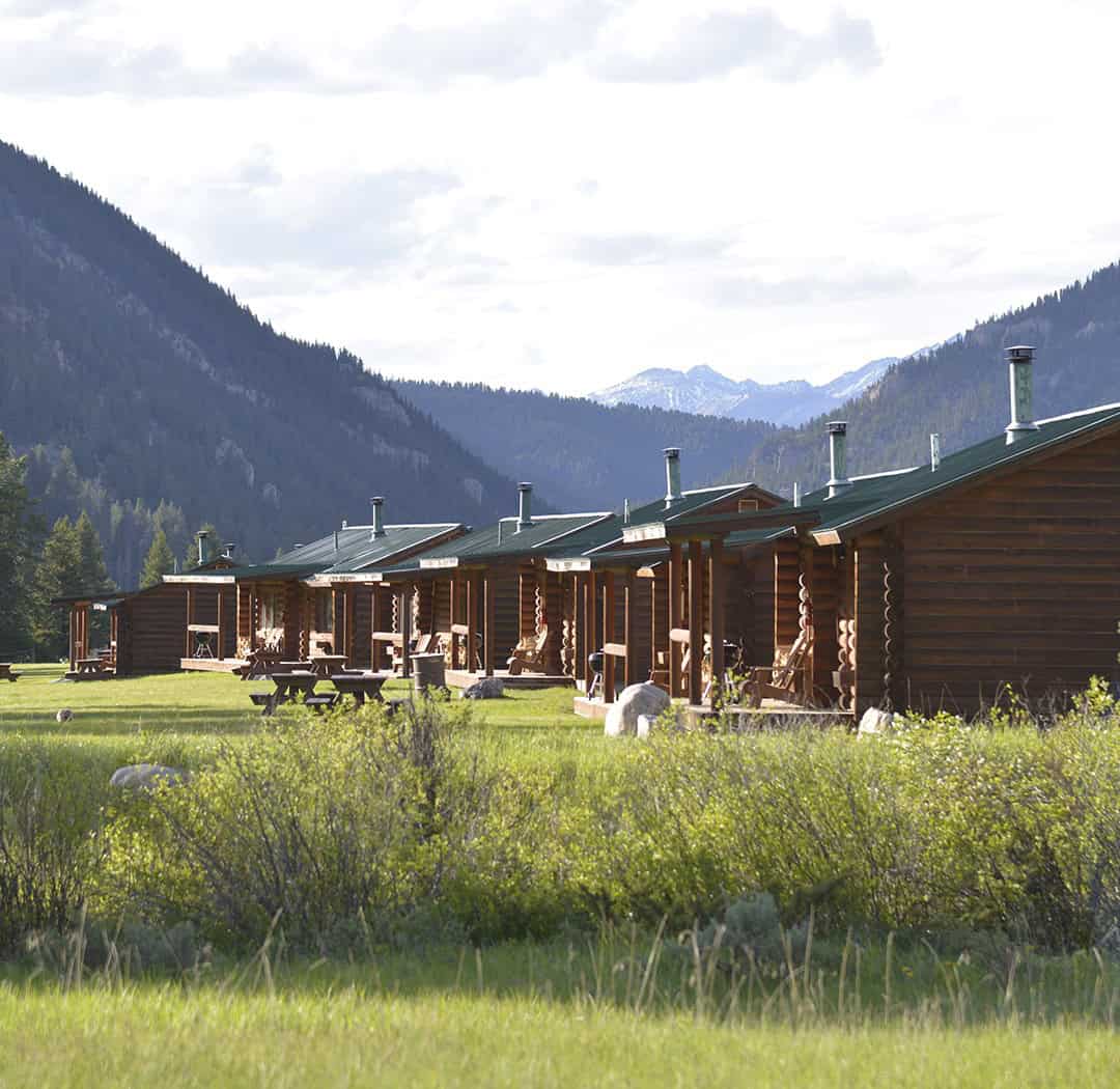 Row of log cabins in a mountain meadow at 320 Guest Ranch in Montana